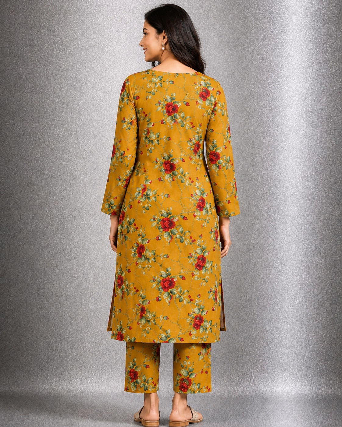Woman modeling a mustard golden 2-piece linen suit with red floral and green botanical prints, featuring a keyhole neckline long kurta and straight trousers.